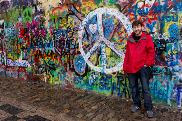 Eine Person steht vor einer Wand mit Graffiti, mit einem Gehweg unten sichtbar.