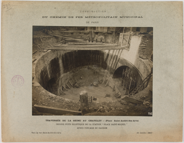 Ein Schwarz-Weiß-Foto eines Tunnels im Bau, mit einem Stempel auf der linken Seite und Text unten.