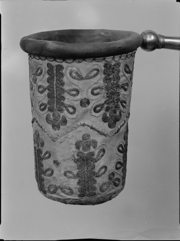 Ein Schwarz-Weiß-Foto eines Stoff-Abfallpapierkorbs mit einem Griff.