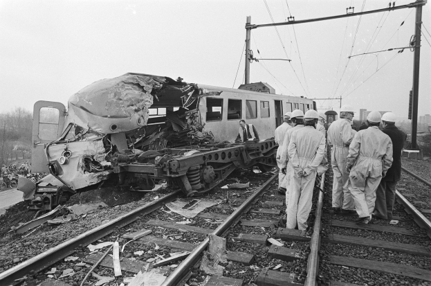 Ein Schwarz-Weiß-Bild eines Zugunglücks auf den Gleisen mit Einsatzkräften in Helmen und sichtbaren Infrastruktur drumherum.
