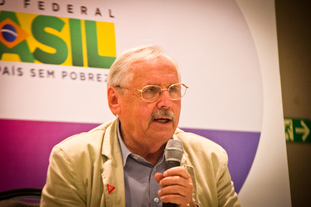 Eine Person, die in ein Mikrofon spricht und im Hintergrund ein Banner mit der Aufschrift "Bundes" sieht.