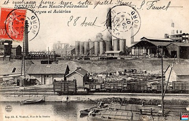 Alte Postkarte mit einer Fabrik im Hintergrund, Häusern, Strommasten, Schiffen und Wasser, mit Stempeln und handgeschriebener Schrift.