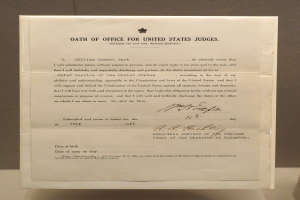 Ein Blatt mit dem Text "Eid für US-Richter" liegt auf einem Tisch vor einer Wand.