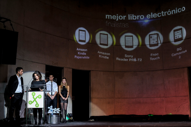 Vier Personen auf der linken Seite, mit einer Frau, die einen Vortrag hält, und im Hintergrund Bilder von Geräten mit ihren Namen darunter.