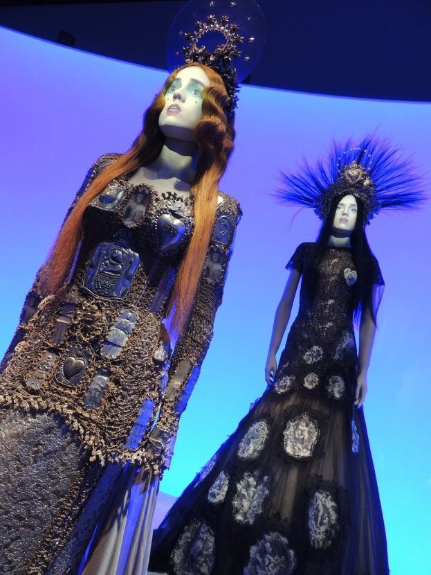 Zwei Schaufensterpuppen mit verschiedenen Kleidern und Kopfbedeckungen.