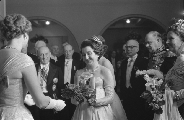 Schwarzes und weißes Foto von Queen Elizabeth II. und Prinz Philip, Duke of Edinburgh, an ihrem Hochzeitstag, die Kronen tragen und Blumensträuße halten, umgeben von einer Gruppe von Menschen.