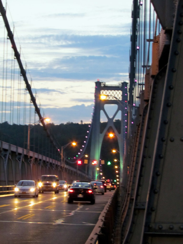 Fahrzeuge auf einer Brücke mit Lichtern, Polen, Hügeln und Himmel im Hintergrund.