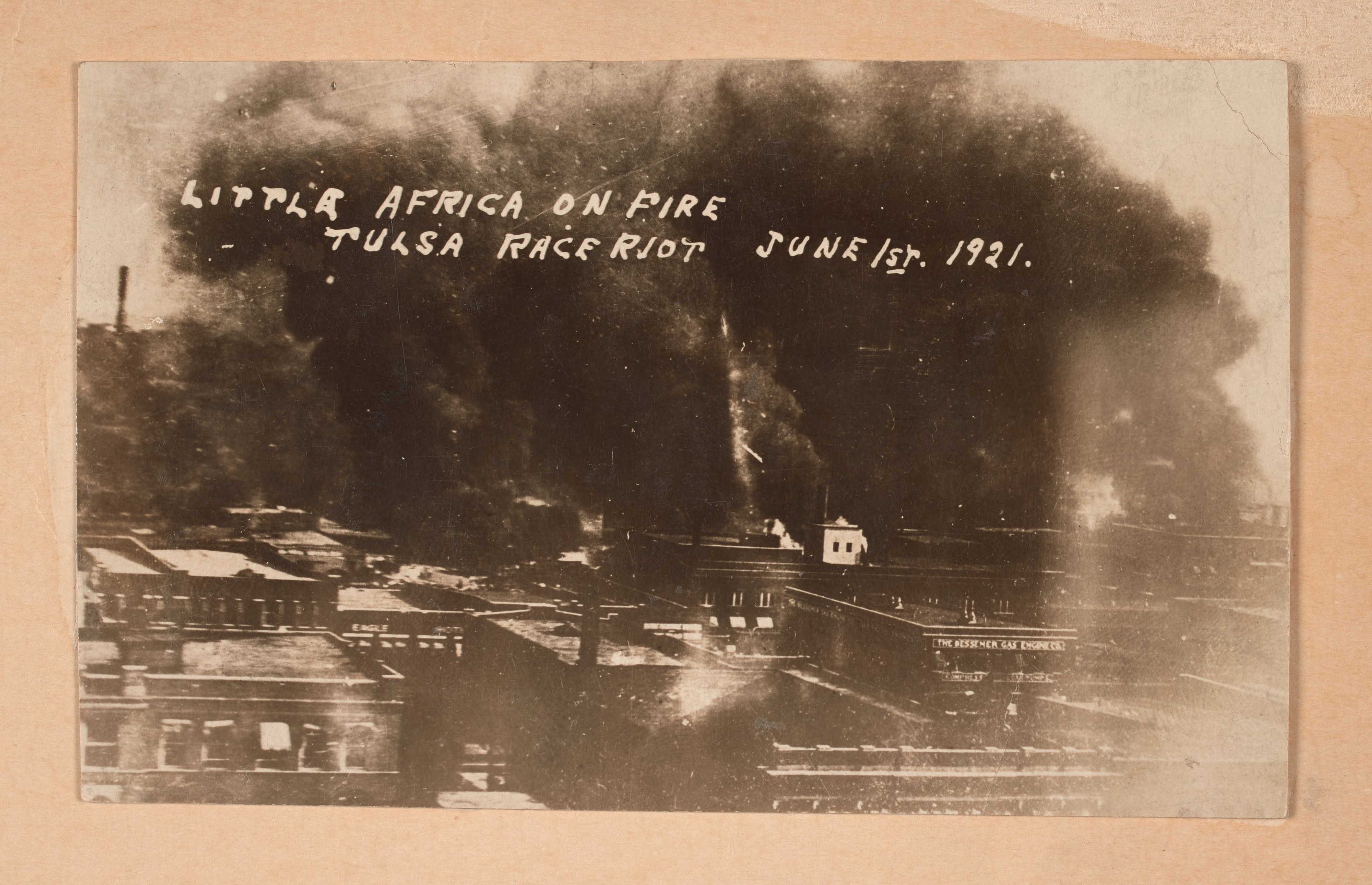 Schwarz-weißes Foto einer Stadt mit Rauch, zentrierter Text und belebten Gebäuden unten.