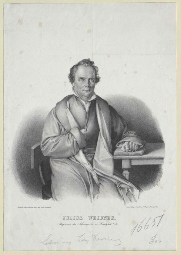 Portrait von Julius Weidner, einem deutschen Philosophen, der an einem Tisch sitzt und ernst in die Kamera schaut, mit einem Anzug und Krawatte, die Hände auf dem Tisch ruhend und direkt in die Kamera blickend, mit Text auf dem Papier vor ihm.
