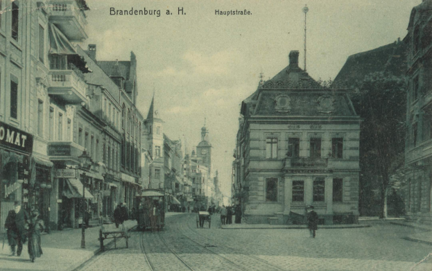 Schwarz-weiß-Foto einer Stadtstraße in Brandenburg, Deutschland, mit Menschen, Bänken, einem Pferdewagen, Gebäuden, Schildern, einer Straßenlaterne, Bäumen und einem bewölkten Himmel.