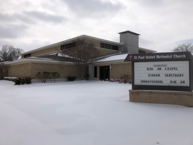 St. Paul United Methodist Church, ein Gebäude mit Fenstern und Türen, umgeben von Pflanzen und Bäumen, mit Schnee auf dem Boden und einem bewölkten Himmel im Hintergrund, mit einer Tafel mit Text auf der rechten Seite.