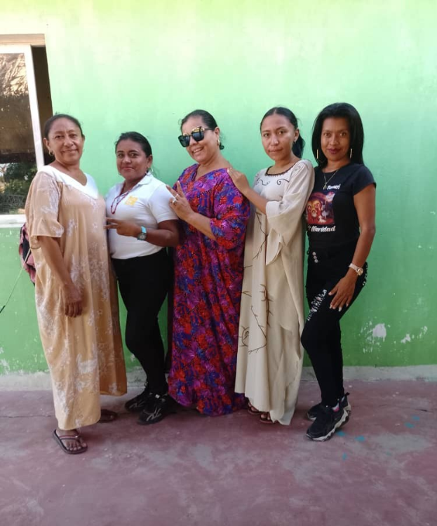 Gruppe von Frauen vor einer grünen Wand mit einem Fenster auf der linken Seite bei einem Internationalen Frauentag-Event.