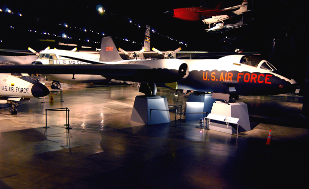 Eine Gruppe von Kampfflugzeugen in einem dunklen Museum mit St├Ąnden, Verkehrskegeln und anderen Gegenst├Ąnden auf dem Boden.