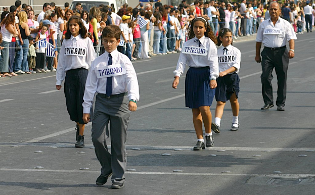 Eine Gruppe von Menschen geht auf der Straße, trägt Abzeichen auf ihren Hemden und ist von einer großen Menge umgeben.