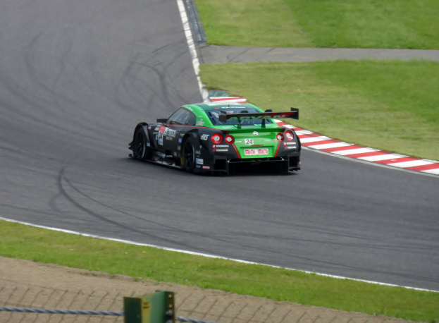 Nissan GT-R Nismo GT3-Rennwagen auf der Nürburgring 24 Stunden-Strecke, umgeben von grünem Gras und einem Zaun unten.