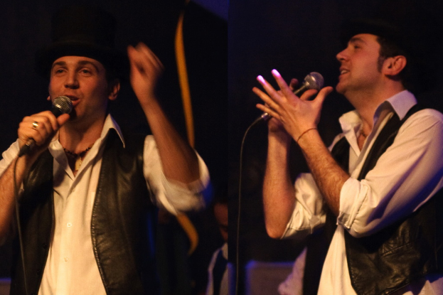 Eine Gruppe von Menschen mit zwei Personen, die in der Mitte in Mikrofone singen.