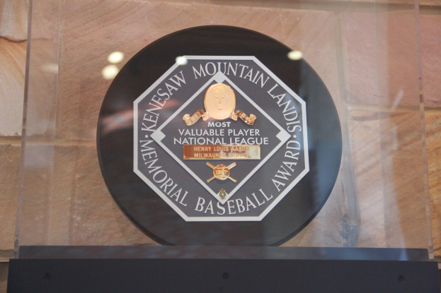 Eine schwarze Plakette an einem Gebäude trägt die Inschrift "Mountain Lands Memorial Baseball Award" mit einer Wand im Hintergrund.