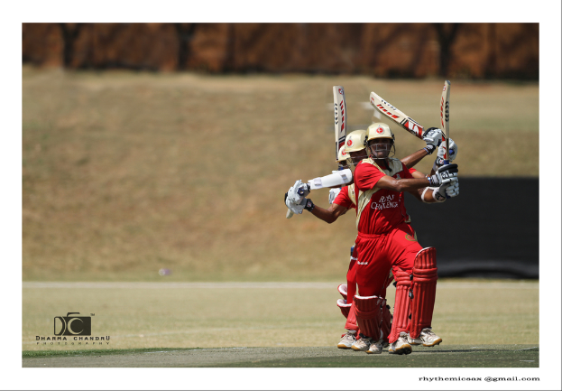 Eine Gruppe von Spielern in einheitlichen Uniformen hält Schläger auf einem Feld mit Wänden im Hintergrund, mit einem Wasserzeichen links unten.