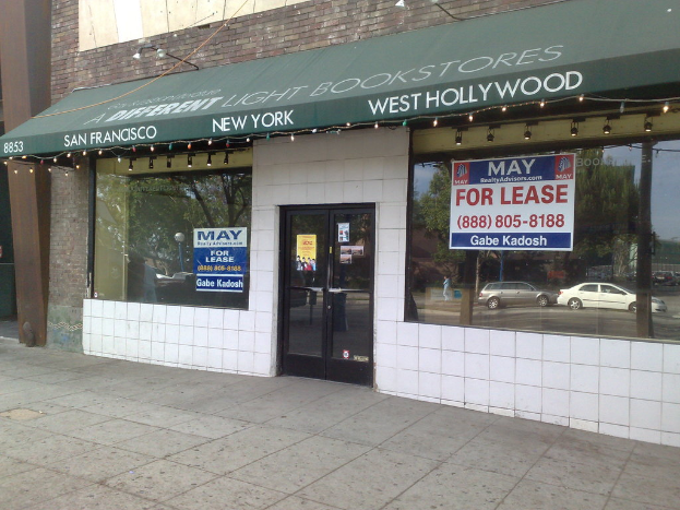 Ein Geschäft mit Glasfenstern und einer Glastür, das die Schatten von zwei Autos an den Fenstern und einen sichtbaren Boden zeigt.
