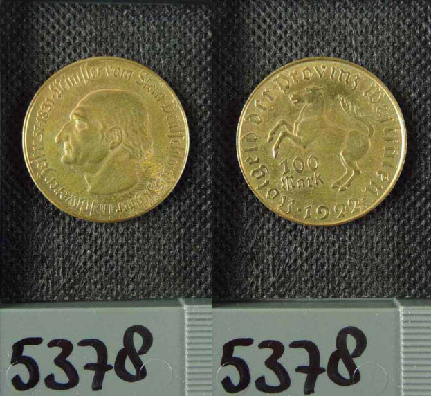 Zwei Goldmünzen aus Deutschland im Jahr 1922, jeweils mit einer Denomination von 100 Mark, die auf einer schwarzen Oberfläche mit Zahlen unten liegen.