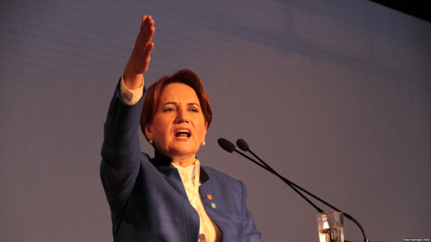 Black Lives Matter-Aktivistin spricht vor einem Publikum mit Schildern, vor Lichtern und anderen Gegenständen an einem Podium mit Mikrofon.