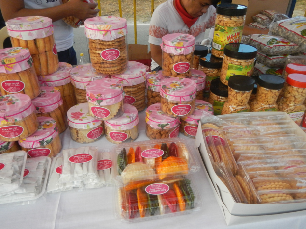 Eine Gruppe von Menschen steht um einen Tisch mit verschiedenen Lebensmitteln auf einem Outdoor-Food-Festival.