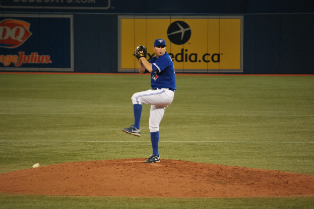 Ein Spieler steht auf dem Feld und hält einen Ball, im Hintergrund ist eine große Fahne mit Text und Bildern zu sehen.