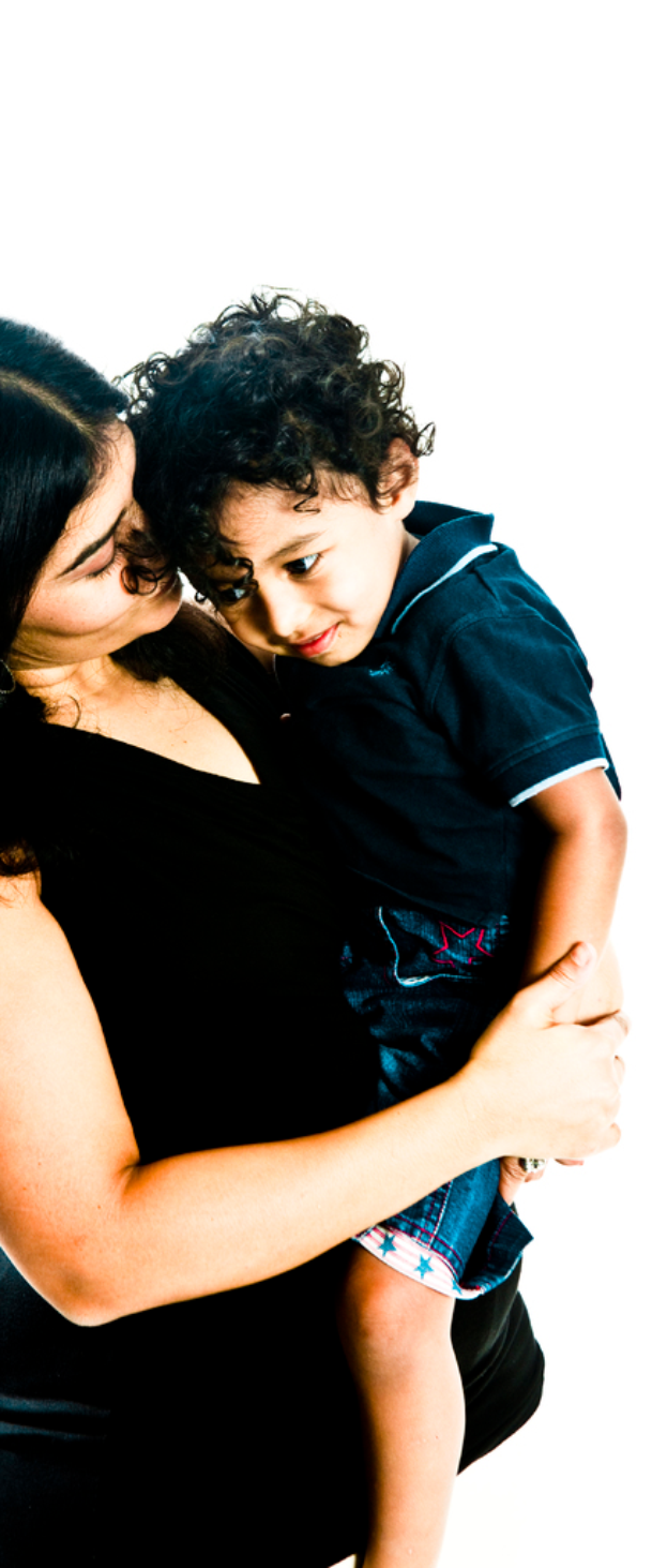 Eine Frau in einem schwarzen Kleid hält ein Kind gegen einen weißen Hintergrund.
