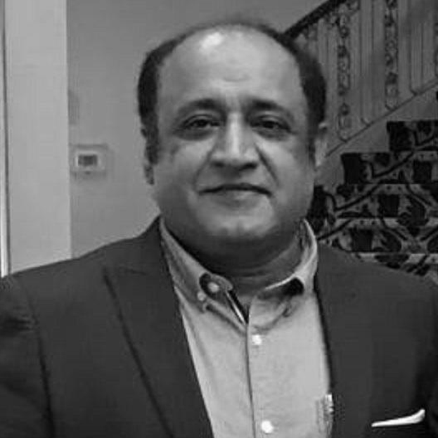 Ein Mann in einem Anzug steht in Bedrängnis vor einer Treppe, mit einer Wand im Hintergrund, auf einem Schwarz-Weiß-Bild.