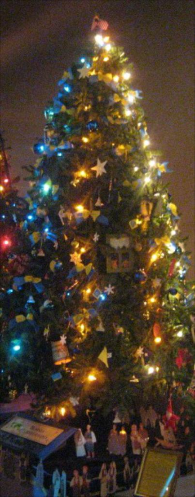 Ein geschmückter Weihnachtsbaum mit Statuen von Menschen auf einem darunterstehenden Tisch.