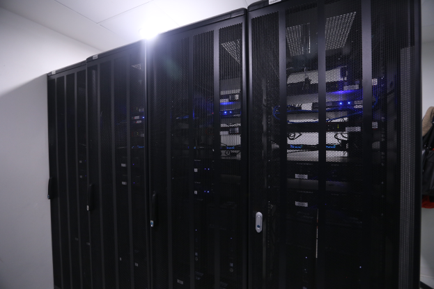 Eine Reihe von Servern in einem Rechenzentrum, ordentlich mit einer Wand im Hintergrund und einer Leuchte oben.