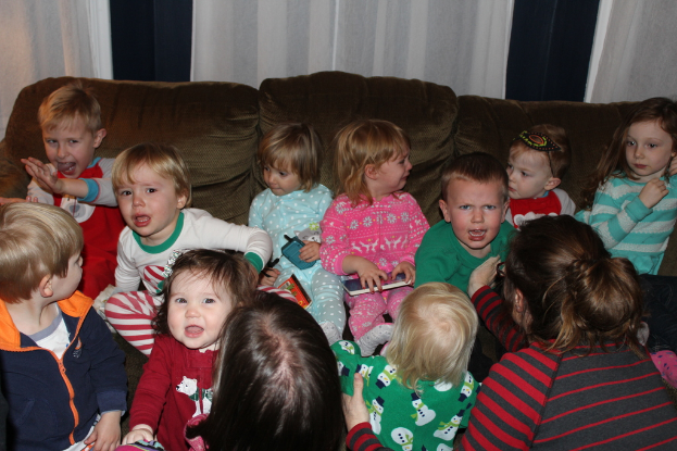 Eine Gruppe von Kindern sitzt auf einem Sofa in einem Raum, jeder hält ein Mobiltelefon, mit einer Frau auf der rechten Seite und einem Vorhang oben.