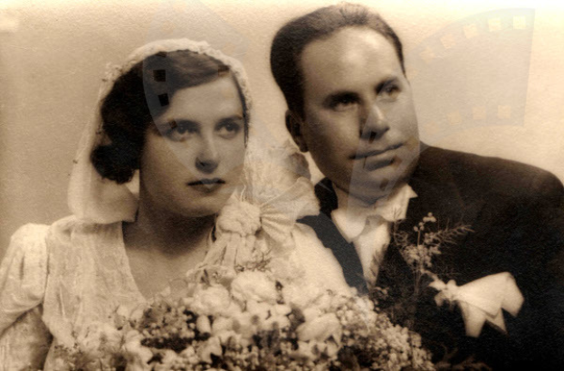 Ein Mann und eine Frau in festlicher Kleidung stehen zusammen und strahlen glücklich auf ihrer Hochzeit, während die Frau einen Blumenstrauß hält.