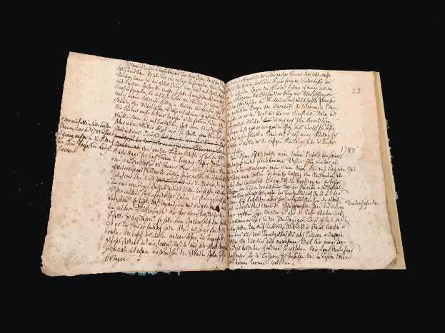 Ein offenes Manuskript aus dem 16. Jahrhundert mit sauberer Schrift auf einem schwarzen Hintergrund.