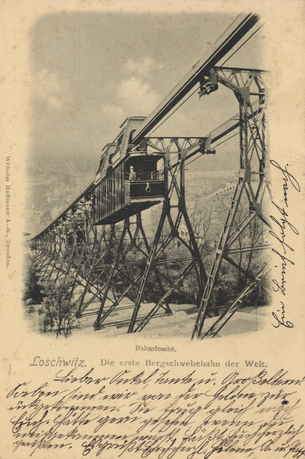 Ein altes Schwarz-Weiß-Foto einer Eisenbahnbrücke mit einem Kran, umgeben von Bäumen und einem bewölkten Himmel, mit Text unten lesend "Bahnstrecka, die erste Eisenbahnbrücke in Deutschland".