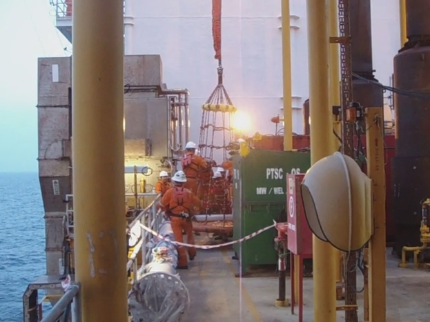 Ein Schiff mit Masten, Kisten und Geländern, das Menschen mit Helmen zeigt, vor Wasser