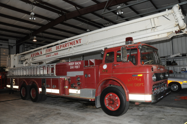 Ein Feuerwehrauto ist in einer großen Lagerhalle mit Deckenbeleuchtung geparkt.