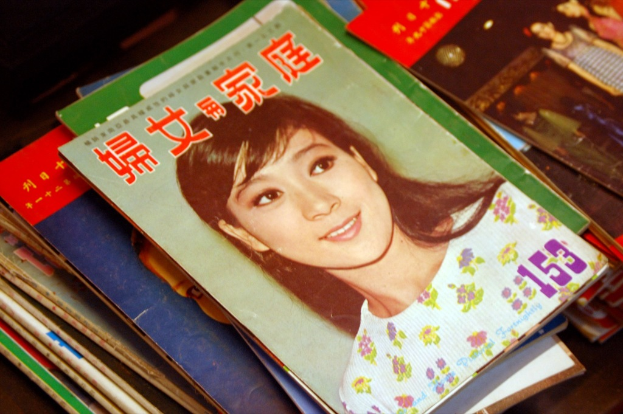 Eine Sammlung von Zeitschriften auf einem Tisch mit dem vordersten, das ein Bild einer Frau zeigt.