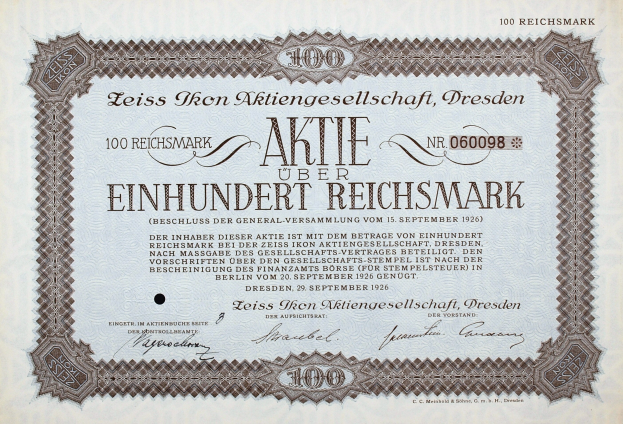Alte deutsche Aktie im Wert von 100 Reichsmark mit schwarzem Rand und gedrucktem Text.