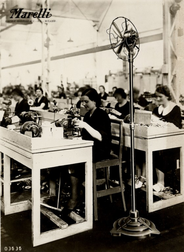 Ein Schwarz-Weiß-Foto von Frauen, die an Nähtischen arbeiten, mit einem Tischventilator im Vordergrund und Text oben.