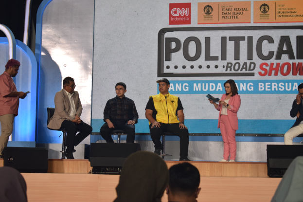 Eine Gruppe von Menschen sitzt auf einer Bühne, einige stehen auf dem Podium, und ein Schild im Hintergrund trägt die Aufschrift "Cnn Political Road Show."
