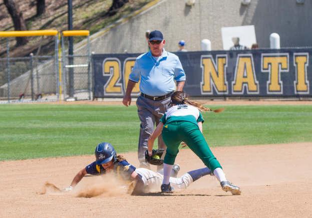 Ein Baseballfeld mit drei Spielern auf rotem Boden, Bäumen, Zaun, Wand, einem Banner mit Text und anderen Gegenständen im Hintergrund.
