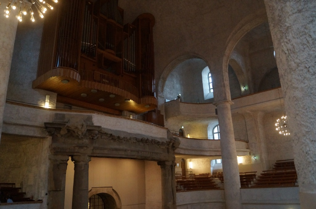 Das Innere eines Gebäudes mit Lampen, Treppen, Säulen, einem hölzernen Objekt an der Wand, Fenstern und Türen.