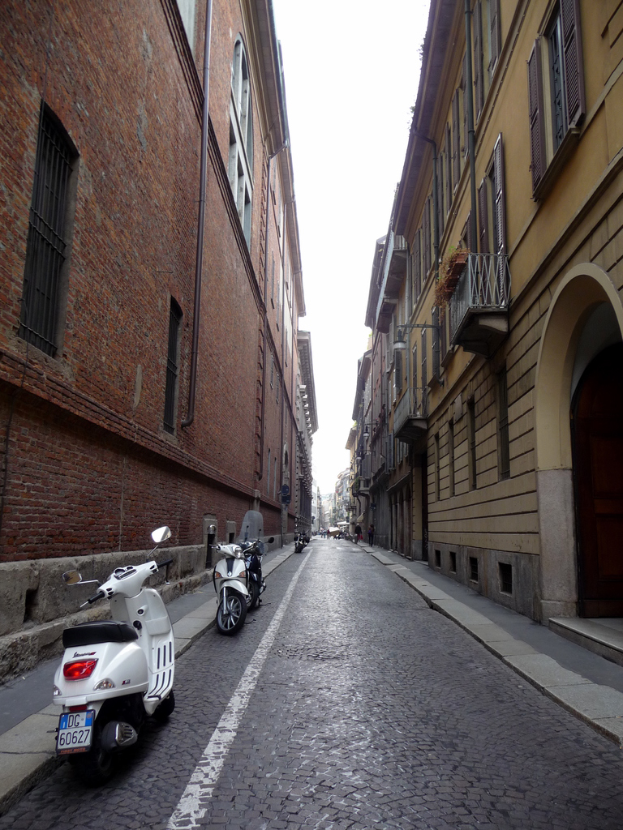 Fahrzeuge parken auf beiden Seiten einer Straße, mit Gebäuden auf beiden Seiten.