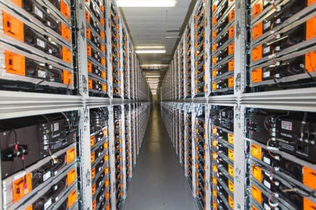 Eine lange Reihe von Servern in einem Rechenzentrum, mit elektronischen Geräten in den Racks und Leuchten oben.