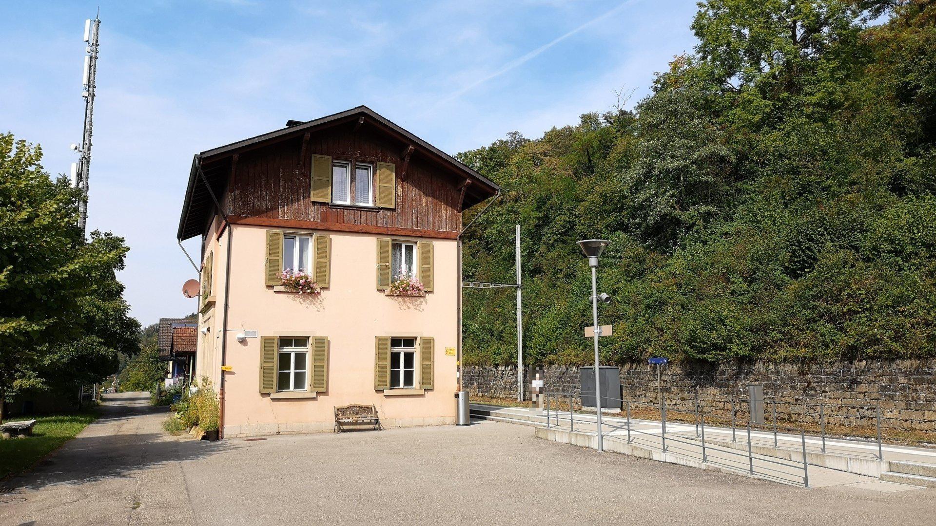 Ferienhaus zum Verkauf in Baden-Württemberg, Deutschland, mit einem Gebäude mit vielen Fenstern, einer Vorderseite, einer Straßenlaterne, Grünflächen und einem bewölkten Himmel.